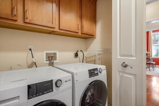 laundry area with wood finished floors, washing machine and clothes dryer, and cabinet space