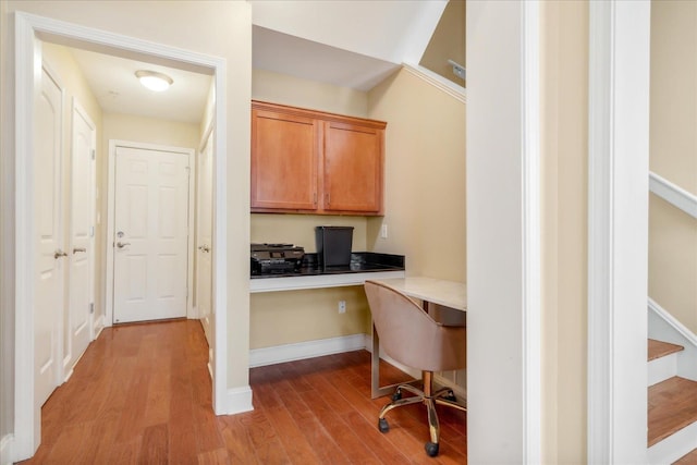 home office with wood finished floors, built in study area, and baseboards