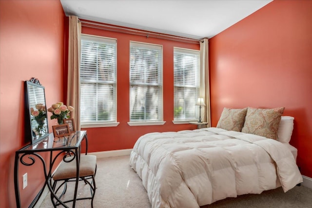 carpeted bedroom featuring multiple windows and baseboards