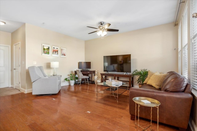 living area with baseboards, a ceiling fan, and wood finished floors