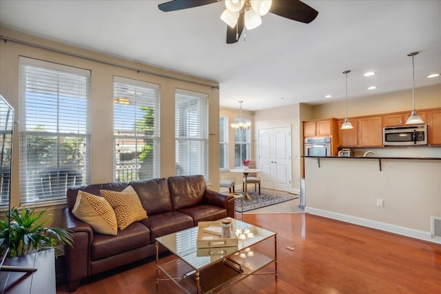 living area featuring recessed lighting, ceiling fan with notable chandelier, wood finished floors, visible vents, and baseboards