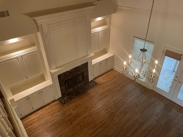 unfurnished living room featuring a high end fireplace, dark wood-type flooring, an inviting chandelier, and built in features