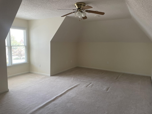 additional living space with ceiling fan, a textured ceiling, light carpet, and vaulted ceiling