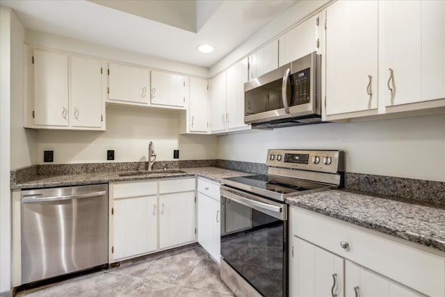 kitchen with dark stone counters, sink, white cabinets, and stainless steel appliances