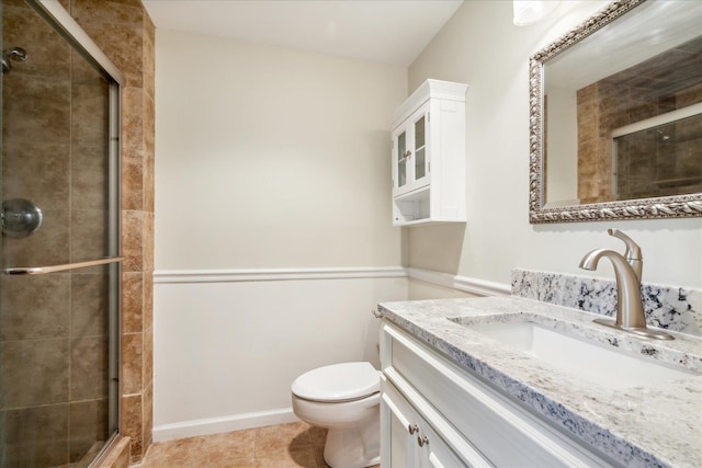 bathroom featuring tile patterned floors, vanity, toilet, and a shower with door