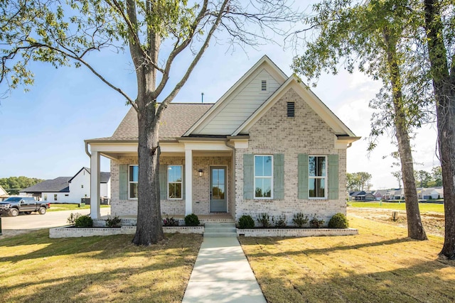 craftsman house featuring a shingled roof, brick siding, and a front lawn