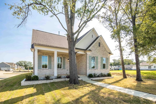 view of front of house featuring brick siding, a front lawn, and roof with shingles