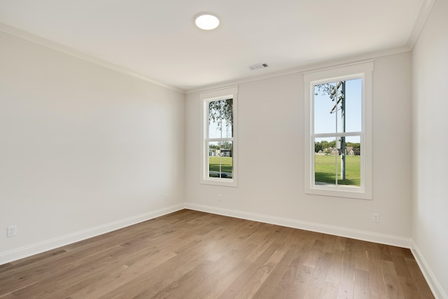 spare room featuring ornamental molding, light hardwood / wood-style floors, and a healthy amount of sunlight