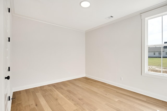 spare room with ornamental molding, visible vents, light wood-style floors, and baseboards