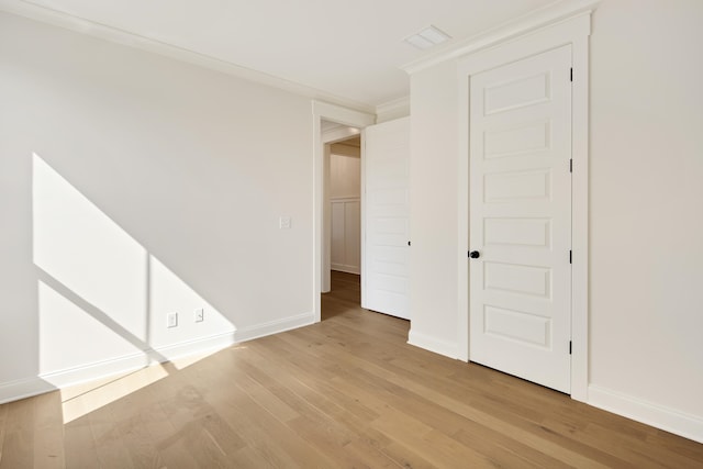 interior space with baseboards, crown molding, and light wood finished floors