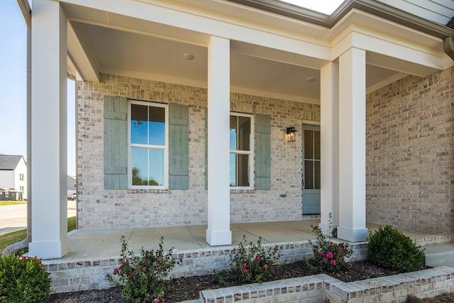 doorway to property featuring covered porch and brick siding