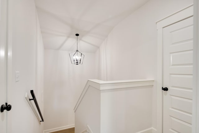 stairway with hardwood / wood-style flooring, an inviting chandelier, and lofted ceiling