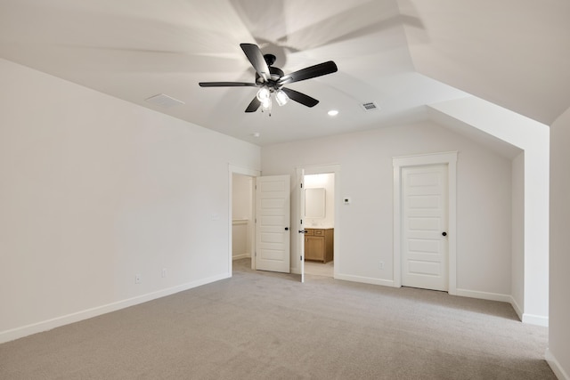 unfurnished bedroom with ceiling fan, light colored carpet, lofted ceiling, and ensuite bath