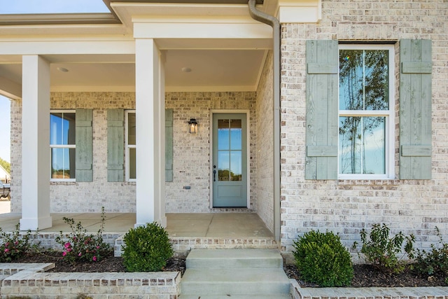 property entrance featuring covered porch and brick siding