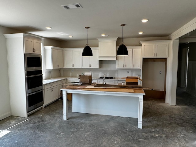 kitchen with wooden counters, custom range hood, a kitchen island with sink, decorative light fixtures, and white cabinetry