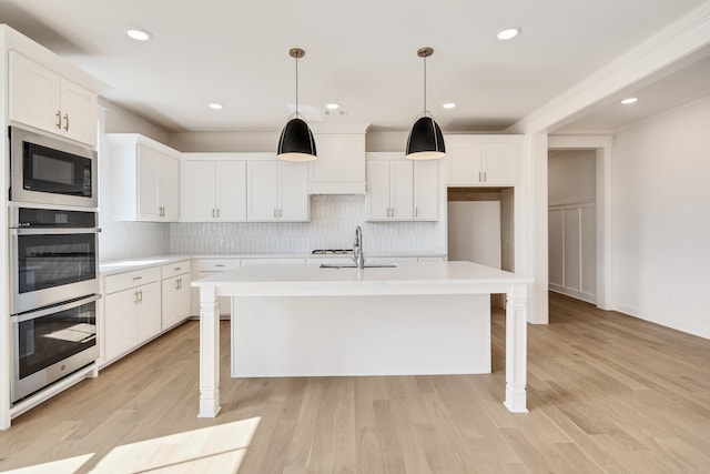 kitchen featuring tasteful backsplash, built in microwave, light countertops, and a kitchen island with sink