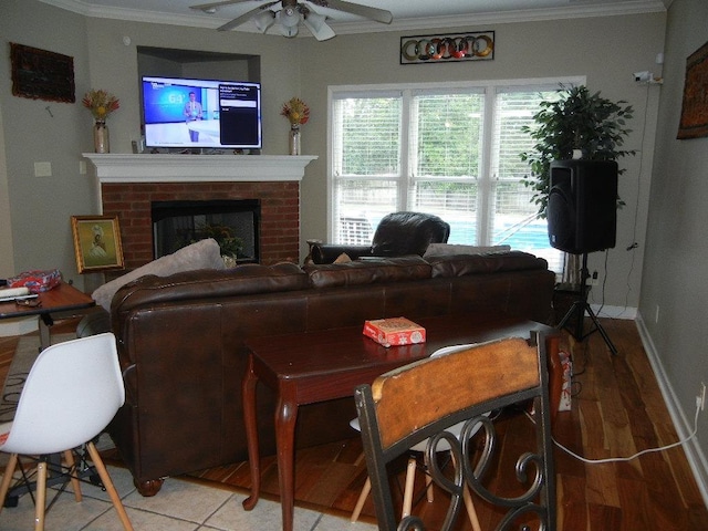 living room featuring a brick fireplace, ceiling fan, hardwood / wood-style flooring, and ornamental molding