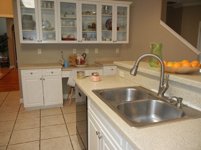 kitchen featuring white cabinets, light tile patterned floors, black dishwasher, and sink