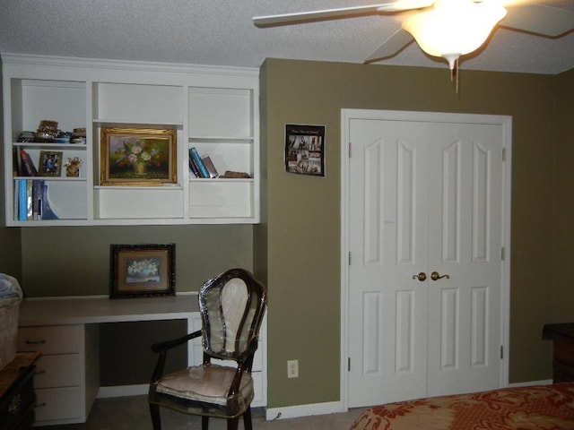 home office with ceiling fan, built in desk, and a textured ceiling