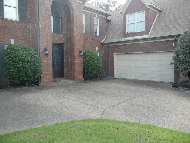 exterior space with brick siding, an attached garage, driveway, and a shingled roof