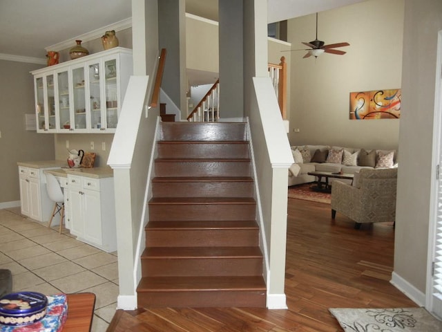 staircase featuring crown molding, ceiling fan, and wood-type flooring