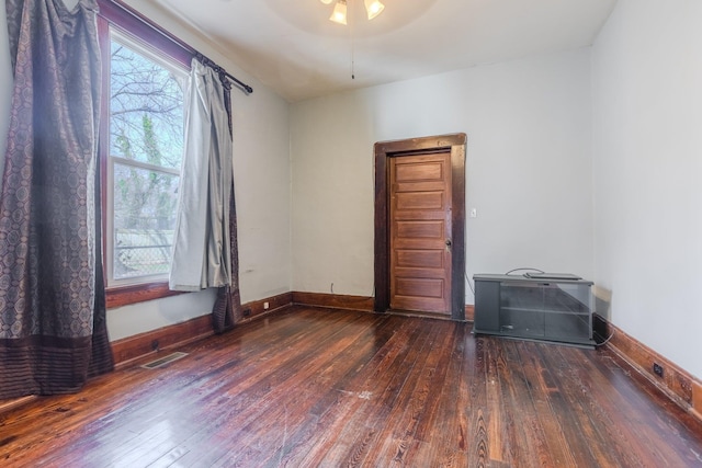 spare room featuring dark wood-type flooring, a healthy amount of sunlight, and vaulted ceiling