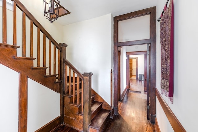 stairs featuring hardwood / wood-style floors and an inviting chandelier