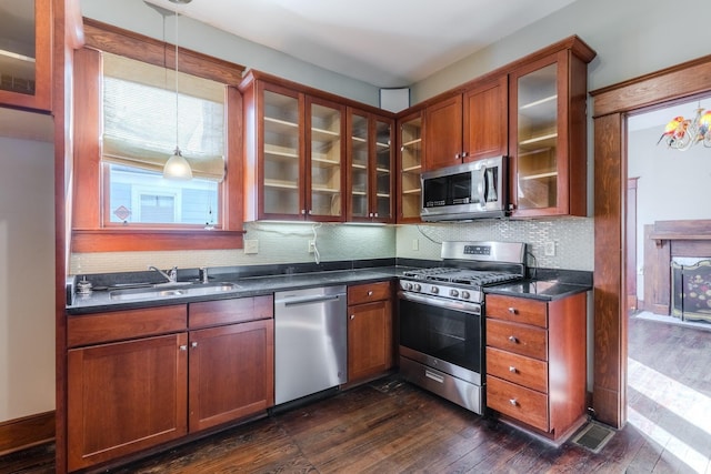 kitchen featuring sink, hanging light fixtures, stainless steel appliances, tasteful backsplash, and dark hardwood / wood-style floors