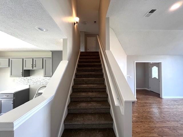 stairs with hardwood / wood-style floors and a textured ceiling