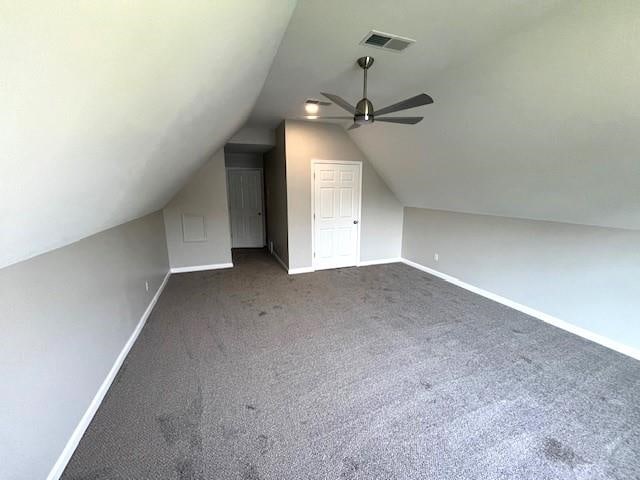 additional living space featuring ceiling fan, dark carpet, and lofted ceiling