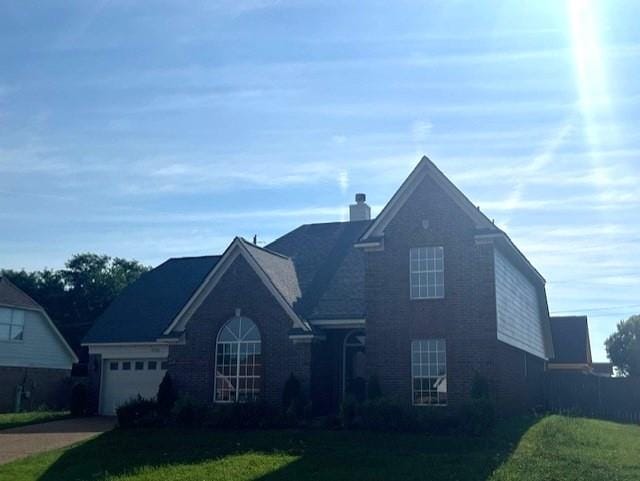 view of property featuring a garage and a front lawn