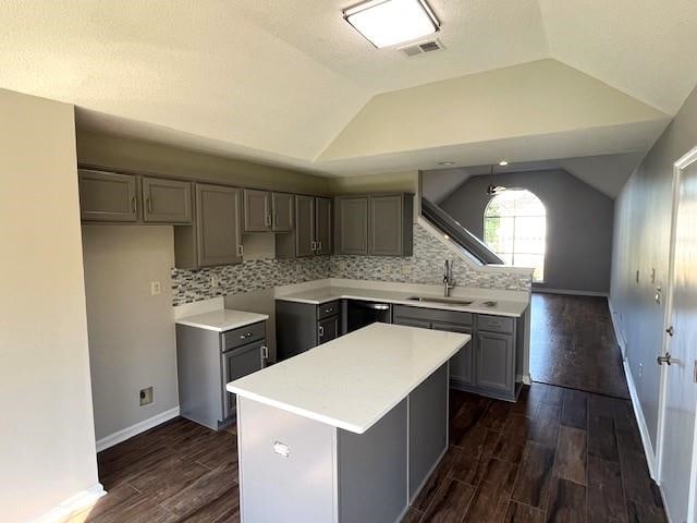 kitchen with gray cabinetry, a center island, sink, vaulted ceiling, and tasteful backsplash