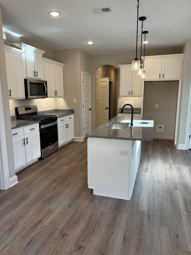 kitchen with dark hardwood / wood-style floors, an island with sink, decorative light fixtures, white cabinets, and appliances with stainless steel finishes