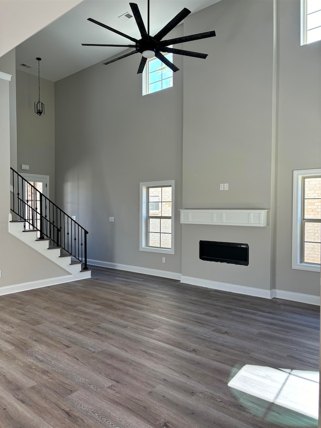 unfurnished living room featuring ceiling fan, a high ceiling, and hardwood / wood-style flooring