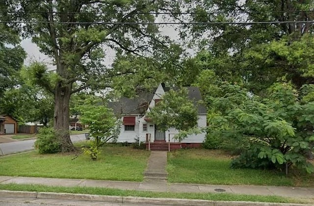 view of property hidden behind natural elements featuring a front lawn