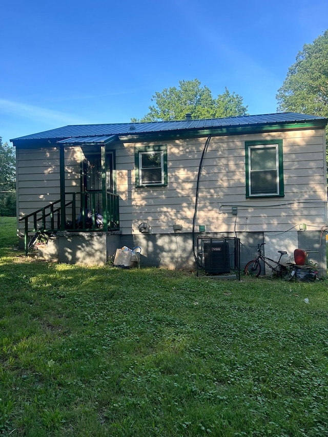 back of property featuring cooling unit and a lawn