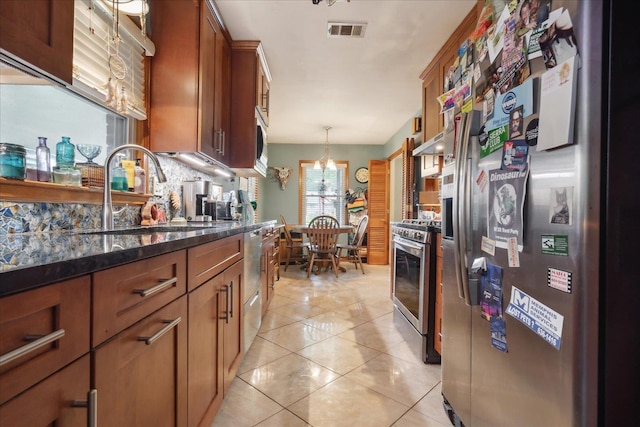 kitchen with tasteful backsplash, dark stone counters, stainless steel appliances, sink, and light tile patterned floors