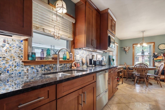 kitchen featuring backsplash, sink, dark stone countertops, decorative light fixtures, and stainless steel appliances