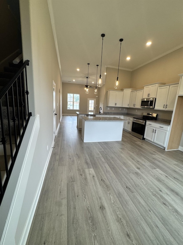 kitchen with hanging light fixtures, a kitchen island, stainless steel appliances, light hardwood / wood-style floors, and white cabinets