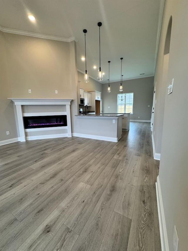 kitchen featuring sink, white cabinetry, decorative light fixtures, light hardwood / wood-style flooring, and ornamental molding