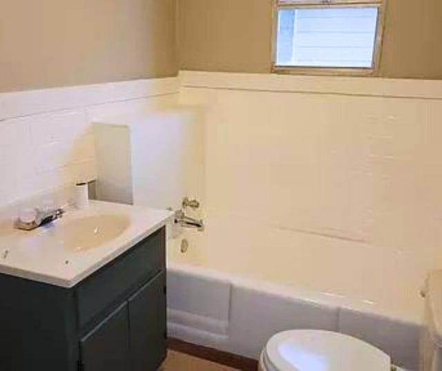 bathroom with vanity, a tub to relax in, and toilet