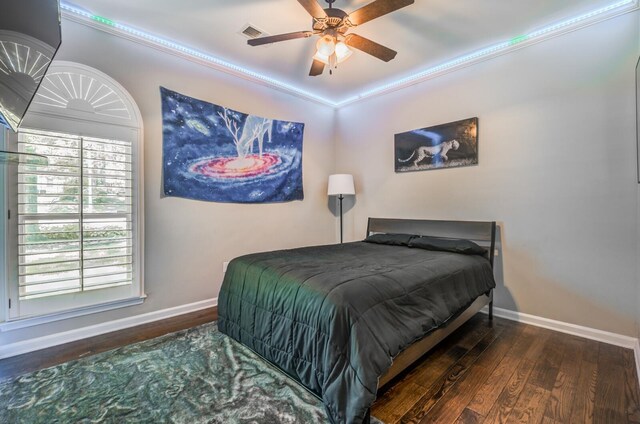 bedroom with visible vents, a ceiling fan, ornamental molding, wood finished floors, and baseboards