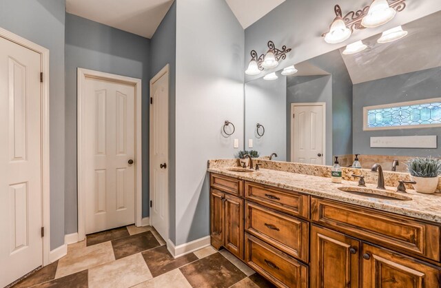 bathroom featuring double vanity, a sink, and baseboards