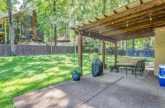 view of patio / terrace featuring a fenced backyard, a trampoline, a fire pit, and grilling area