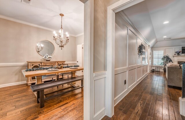 dining area with ornamental molding, a fireplace, dark wood finished floors, and a decorative wall