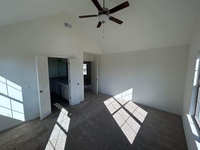 interior space with dark carpet, high vaulted ceiling, and plenty of natural light