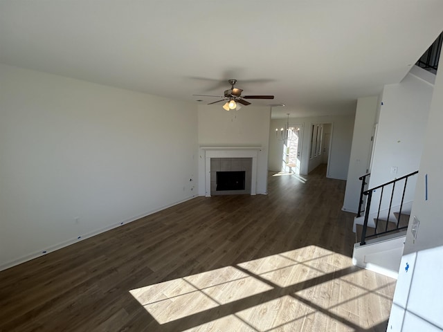 unfurnished living room featuring a fireplace, ceiling fan with notable chandelier, and hardwood / wood-style flooring