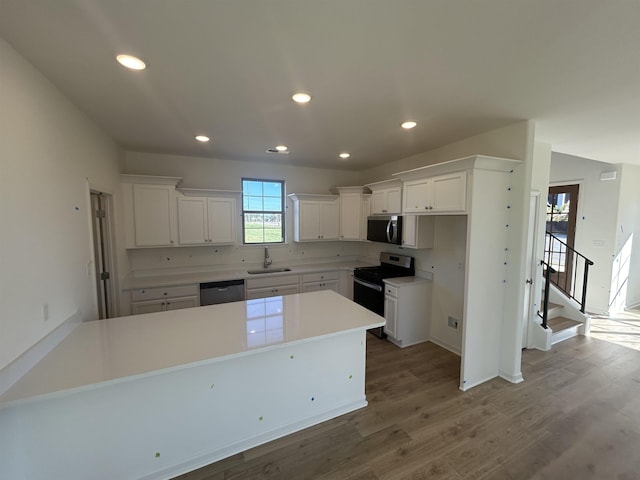 kitchen featuring white cabinets, hardwood / wood-style floors, stainless steel appliances, and a kitchen island