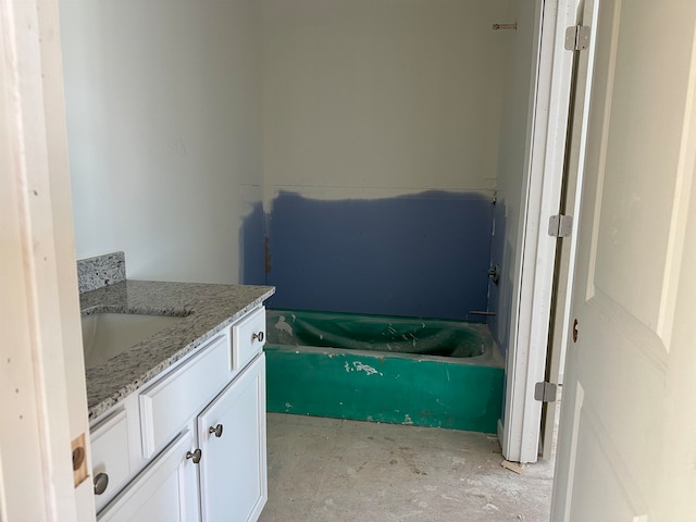 bathroom with a bathtub, vanity, and concrete floors