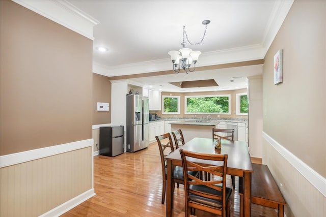 dining space featuring light hardwood / wood-style flooring, ornamental molding, and a notable chandelier